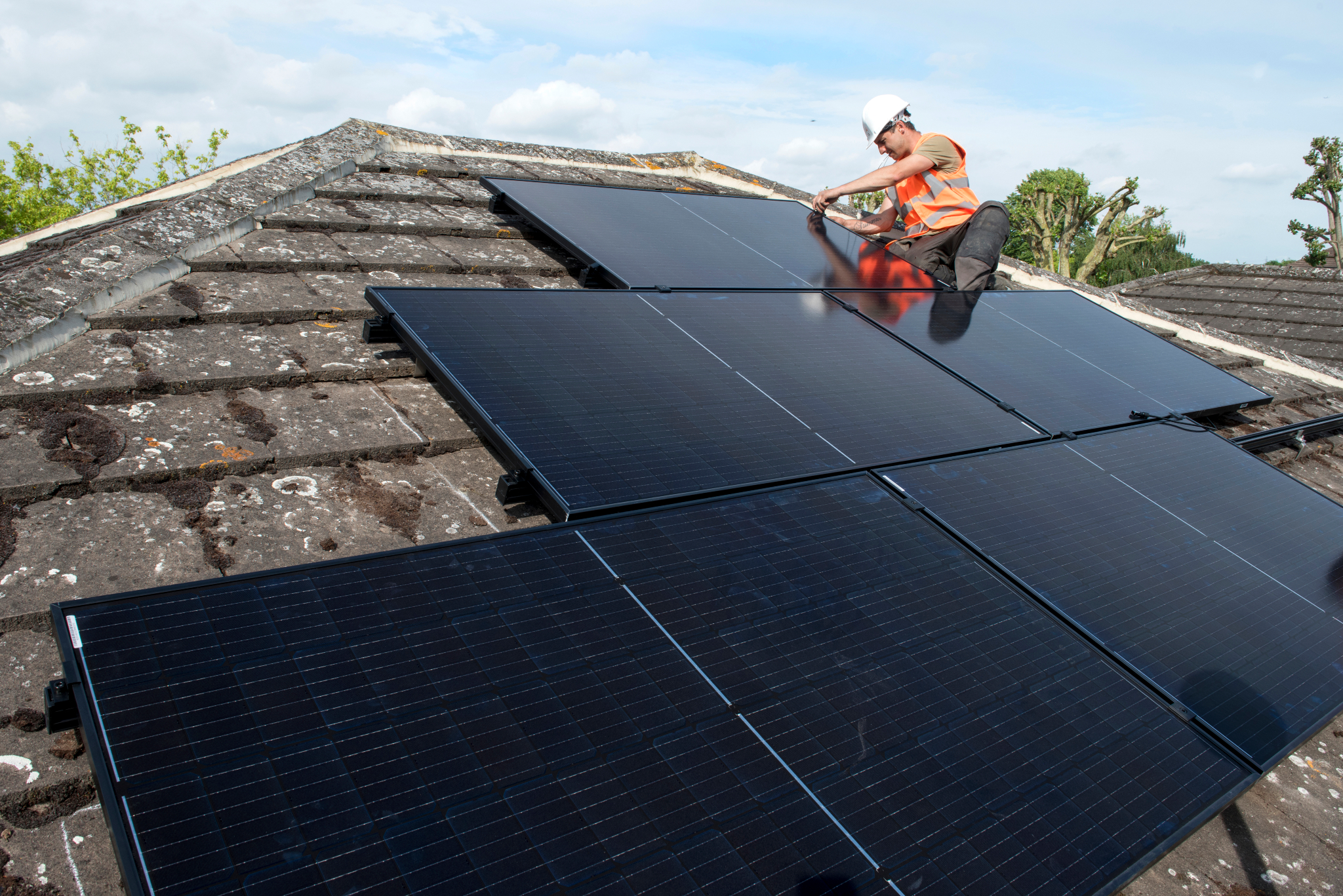 A male roofer installing solar panels on a house