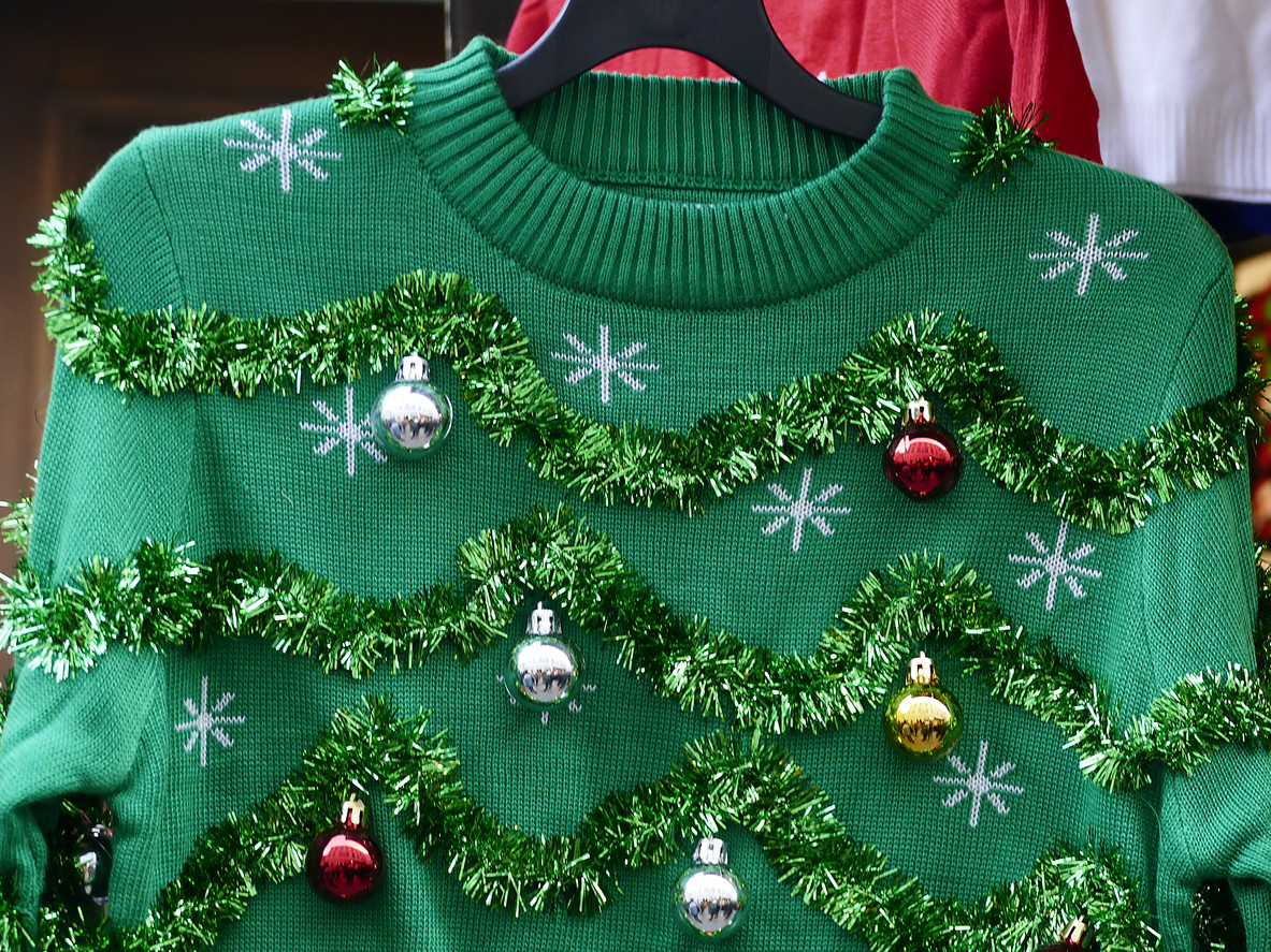 A green Christmas jumper with tinsel and baubles on it