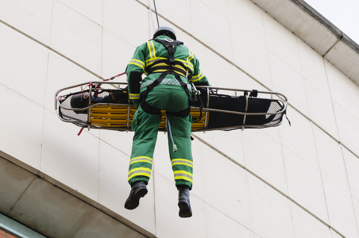 A man being lowered from a building on a stretcher