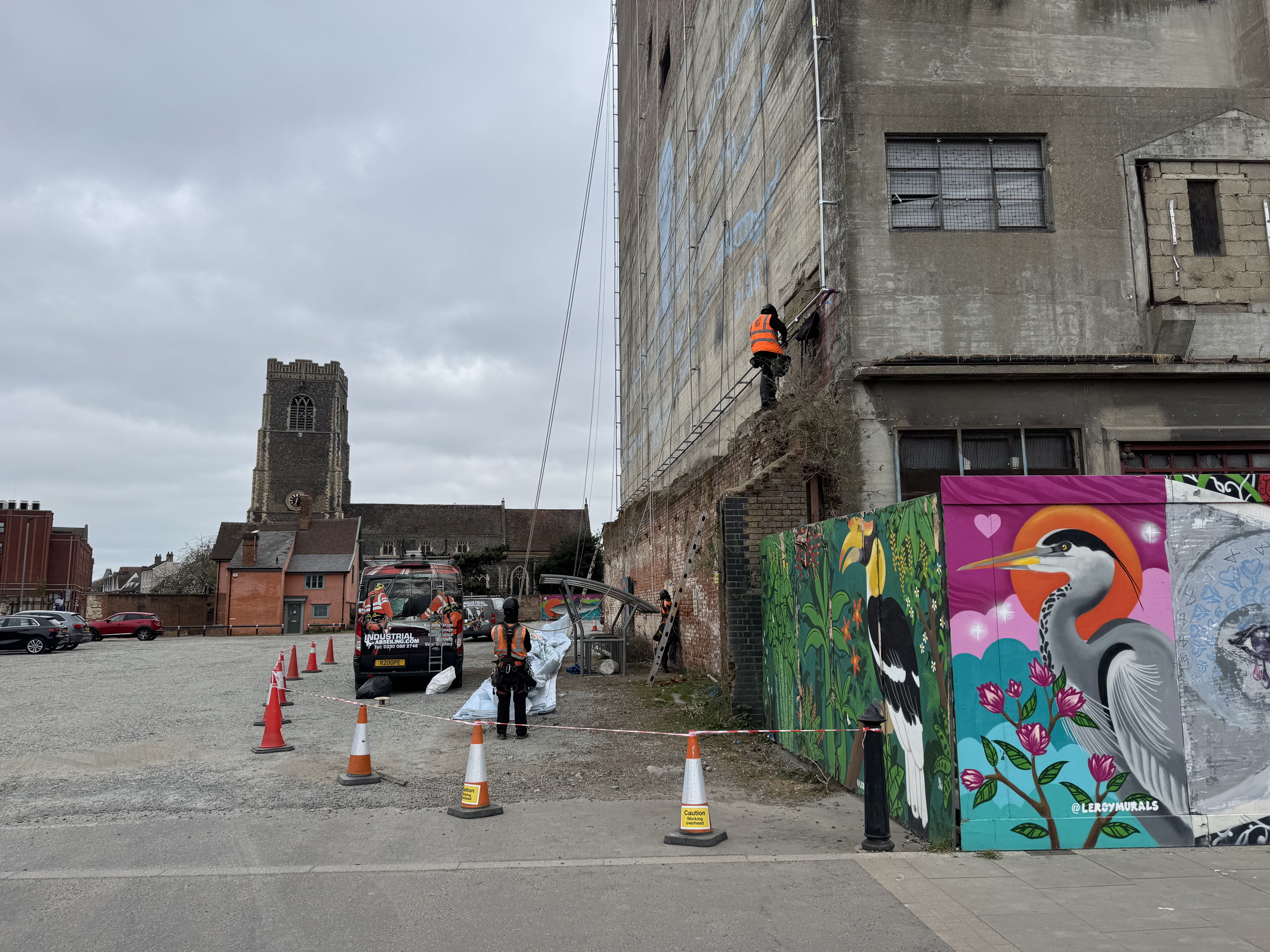Industrial abseilers attach ropes and pulleys to the frame and canvas