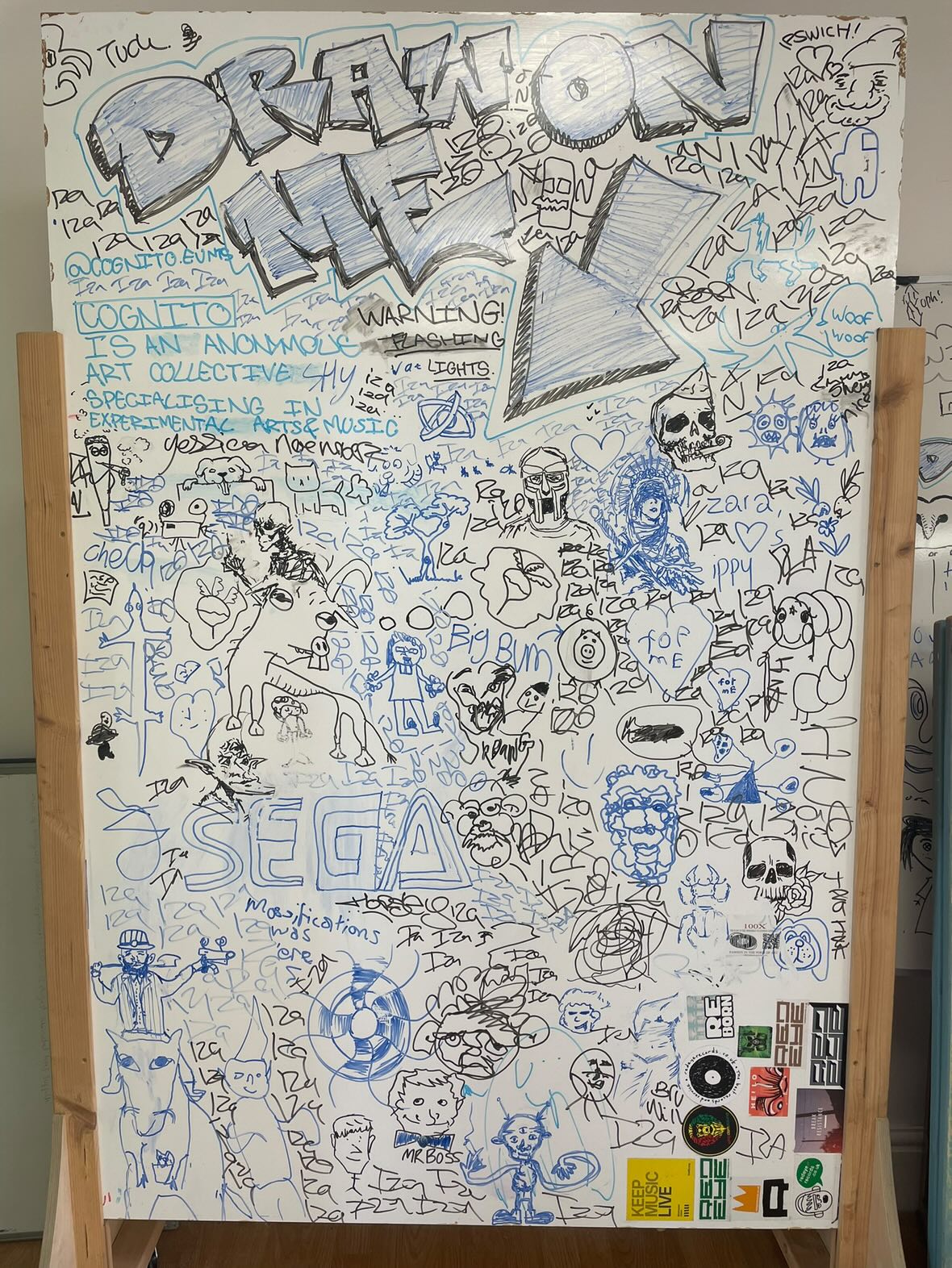 A low-fi interactive art installation on a white board inviting attendees to contribute