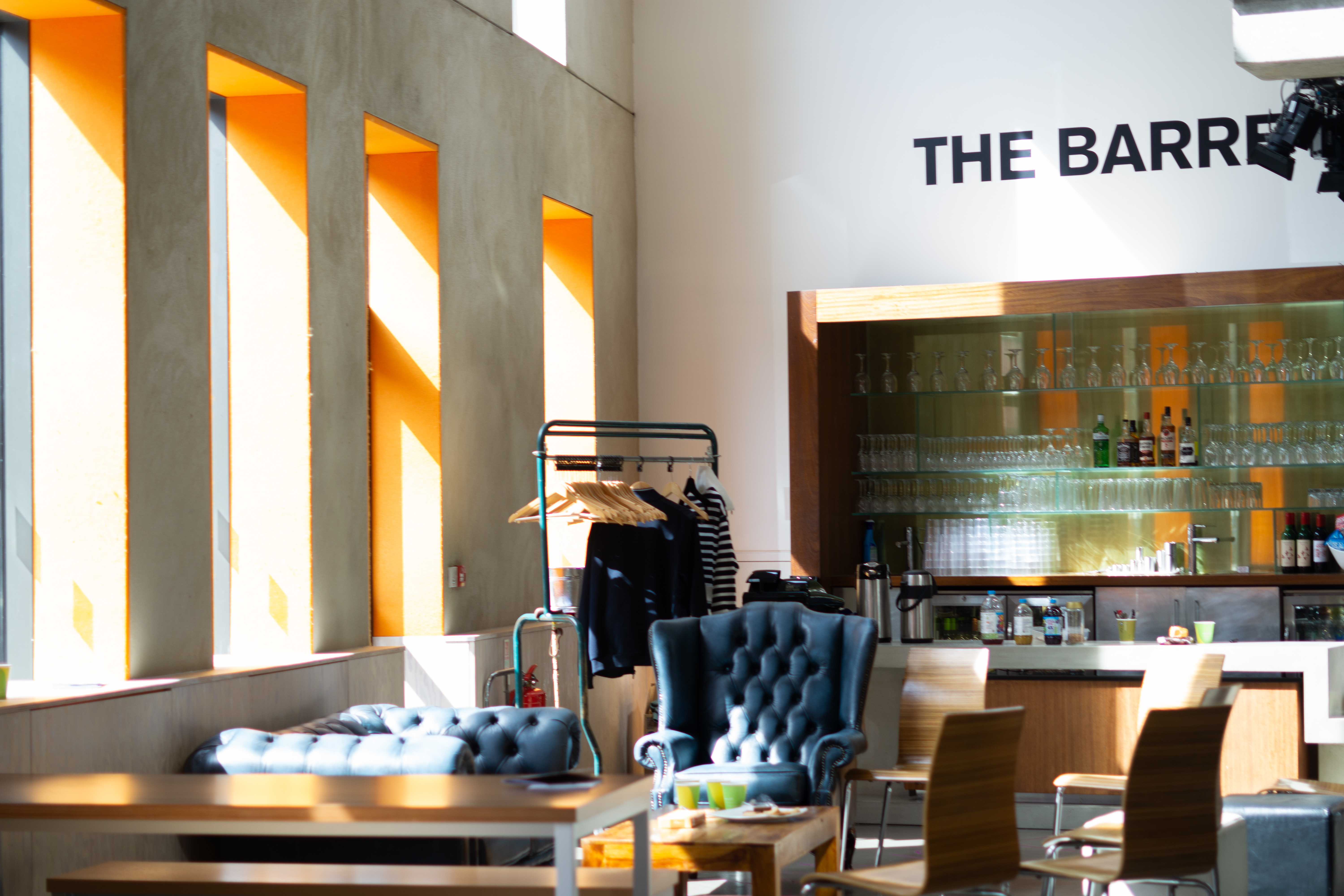 Interior of DanceEast showing modern seating area with comfortable chairs, warm lighting, and bar area designed for community engagement