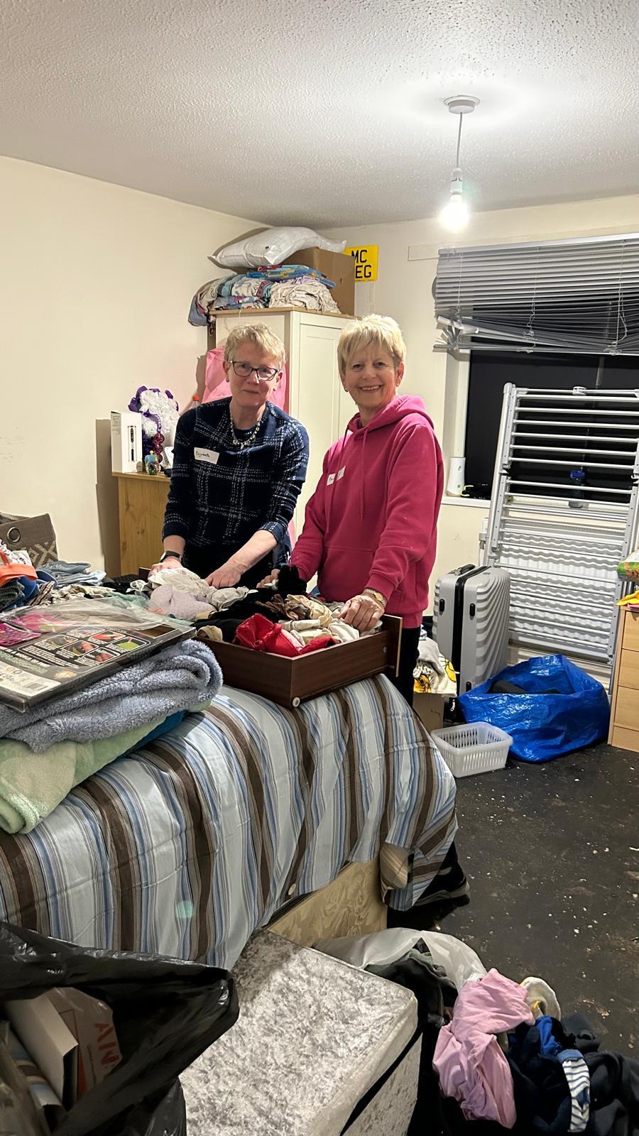 Volunteers sorting and organising belongings in a bedroom during an active Dora Brown shift