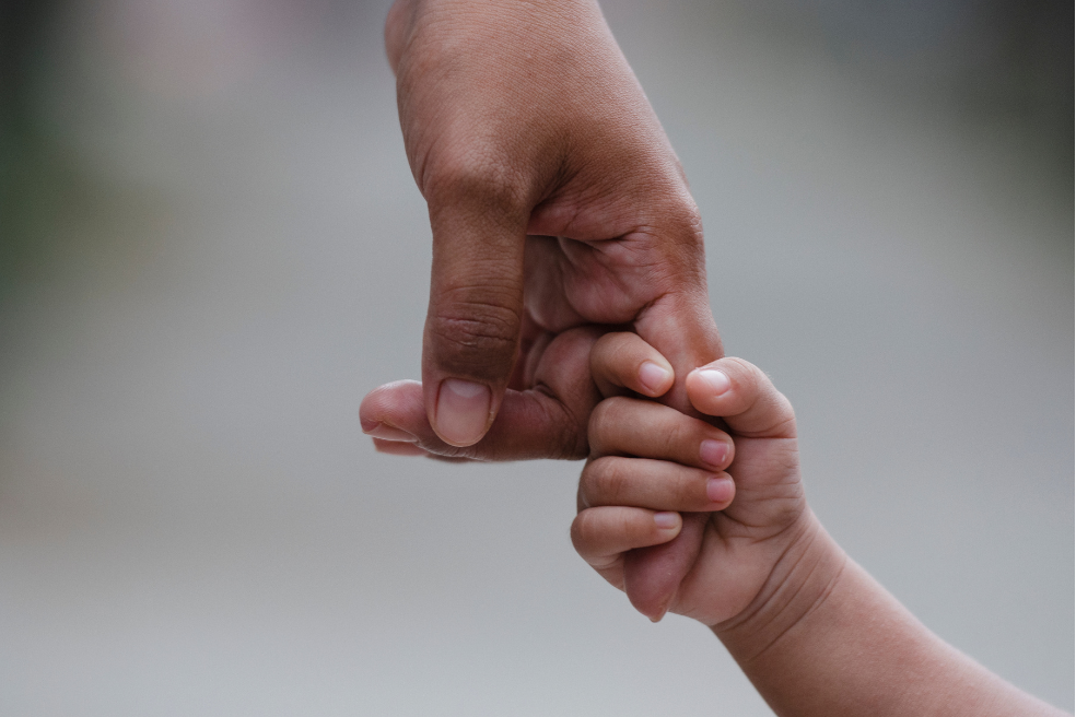 Photo of a child's hand gripping onto an adult's finger