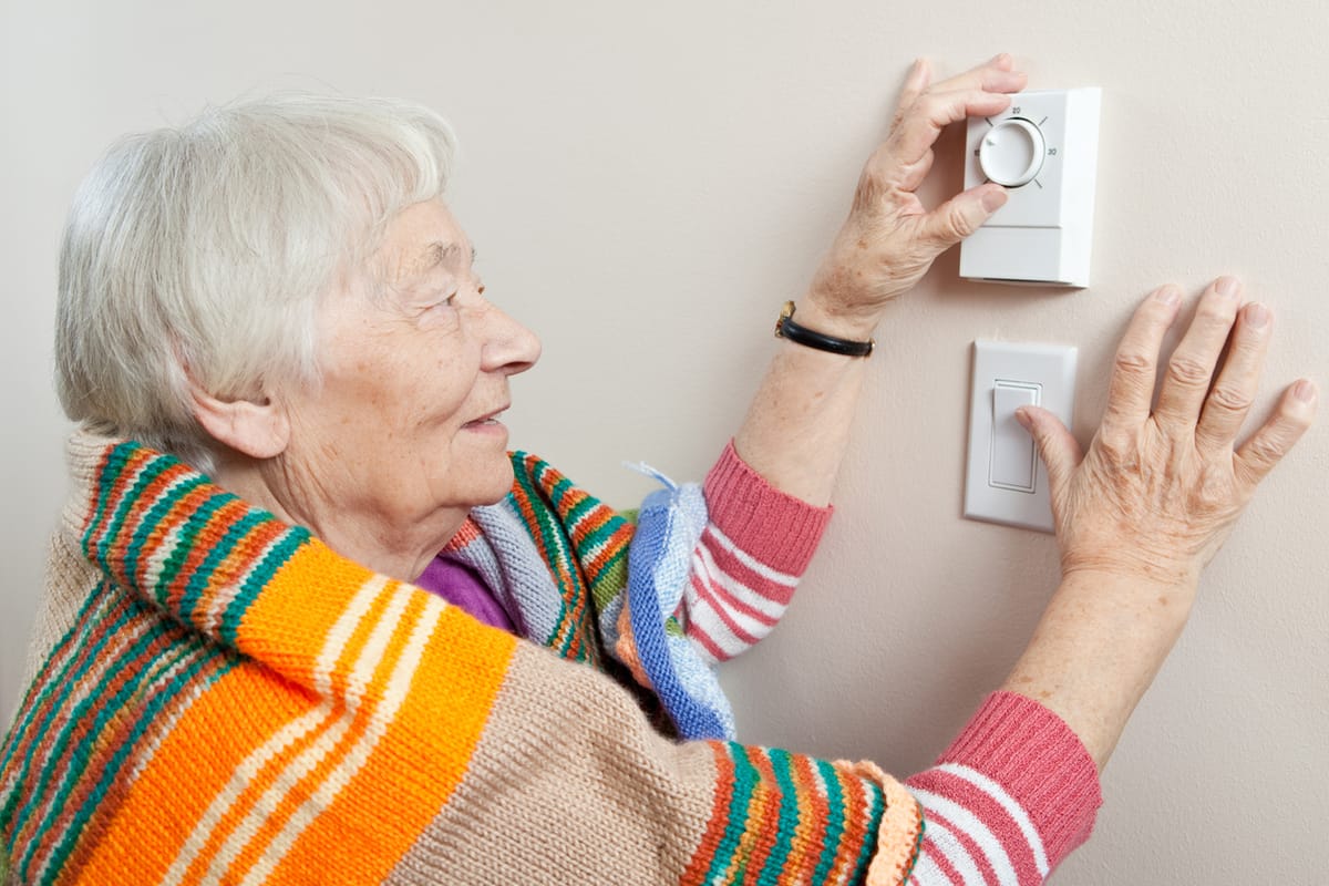An elderly lady turning up the heating