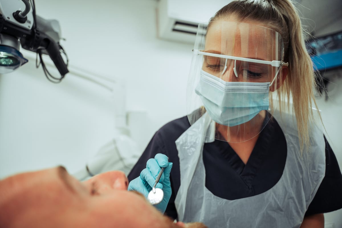 A female dentist looking at a male patient's mouth