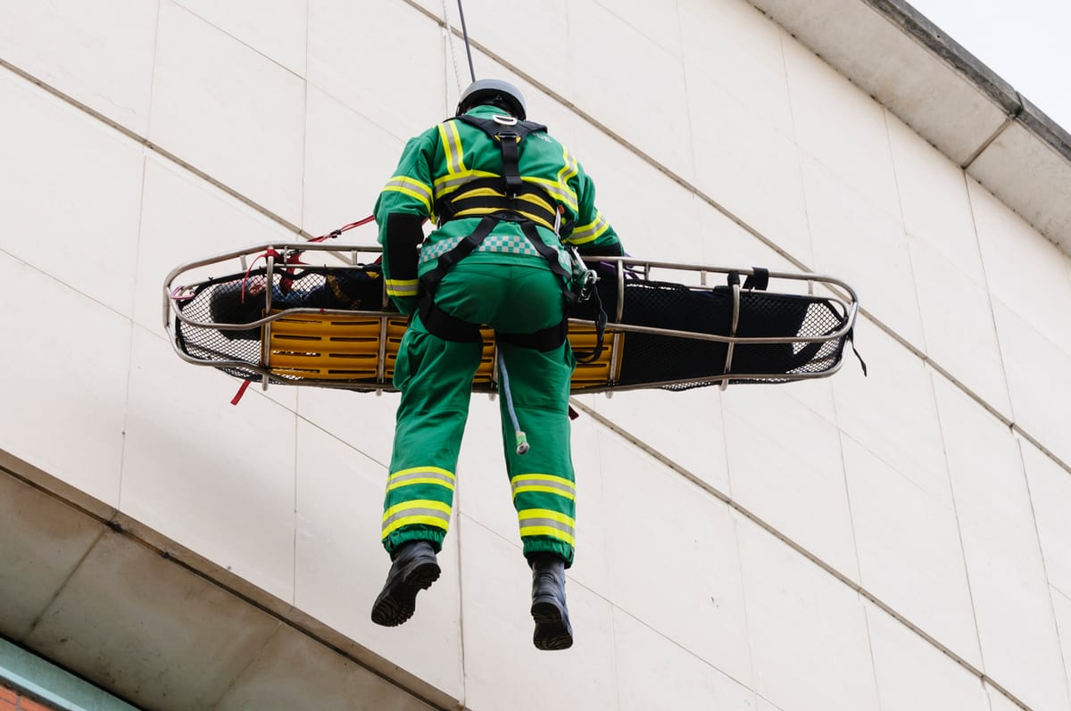 A man being lowered from a building on a stretcher