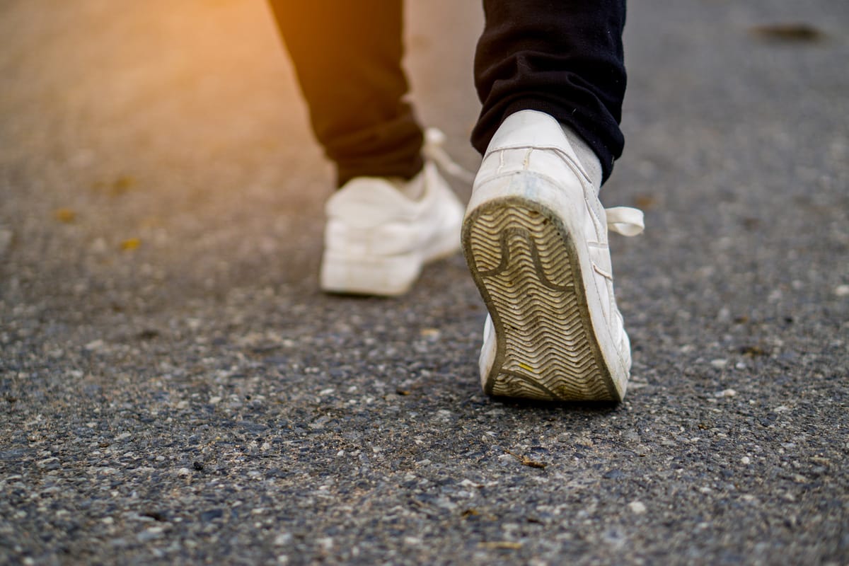 A close-up of a man walking on the pavement
