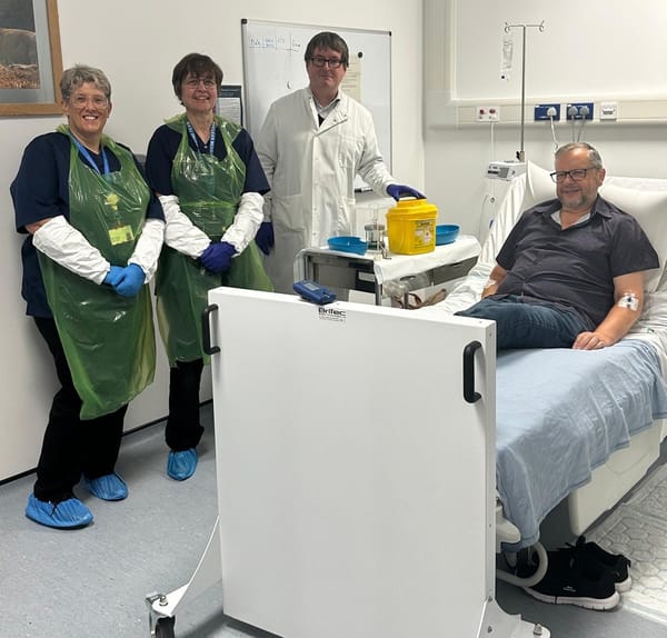 A doctor and two nurses standing next to a patient's bed