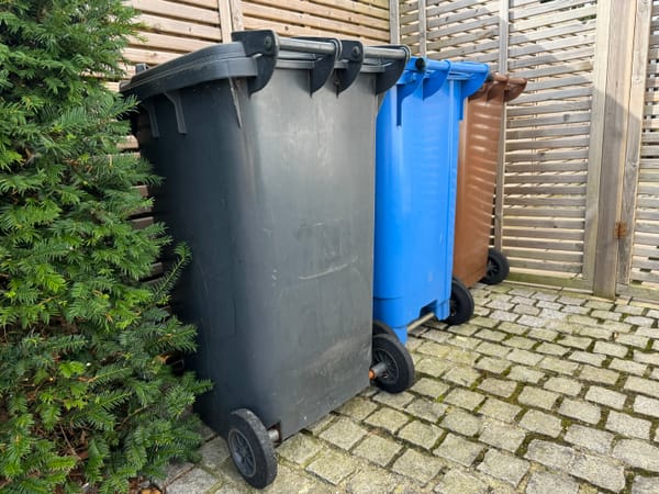 A black bin, brown bin and blue bin