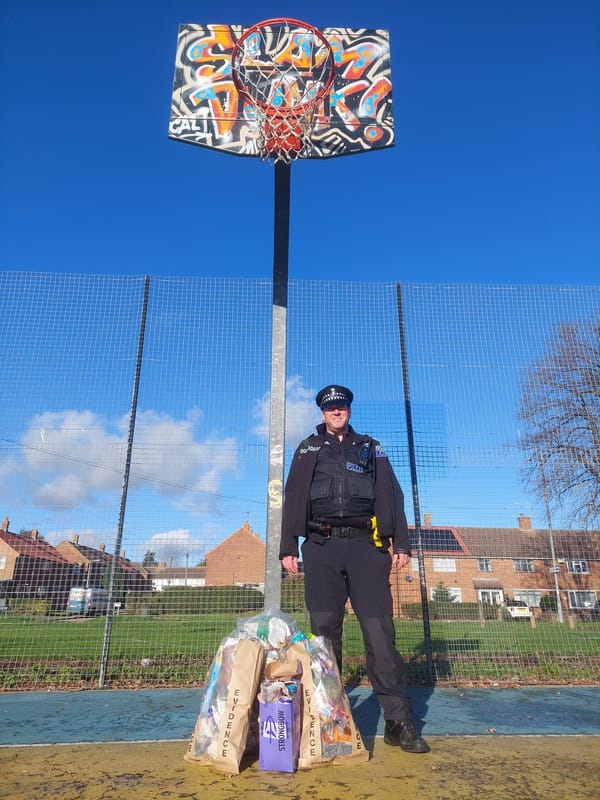 An Ipswich police officer with three evidence bags of rubbish after the clean-up at Hawthorne Drive basketball court in Ipswich