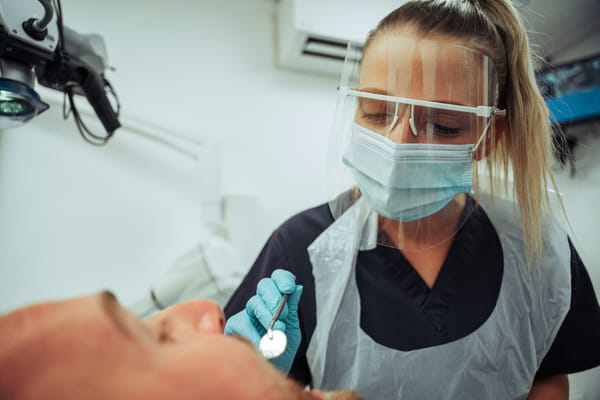 A female dentist looking at a male patient's mouth
