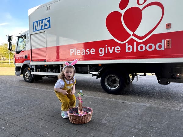 Etta giving out Easter eggs at the hospital in front of a Please Give Blood truck
