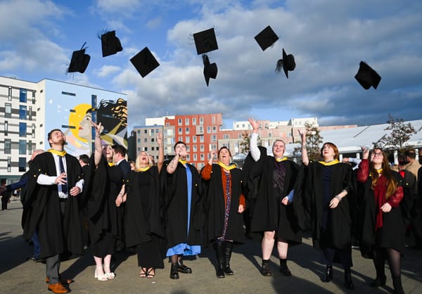 young people throwing hats in air